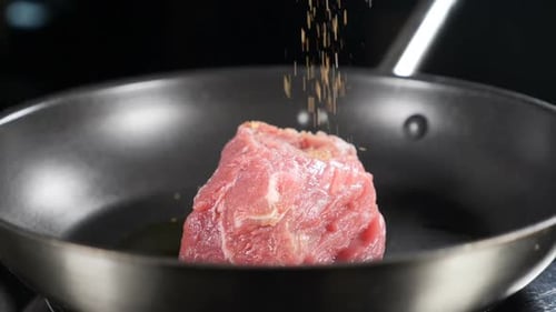 Seasoning Raw Pork in a Skillet Close Up