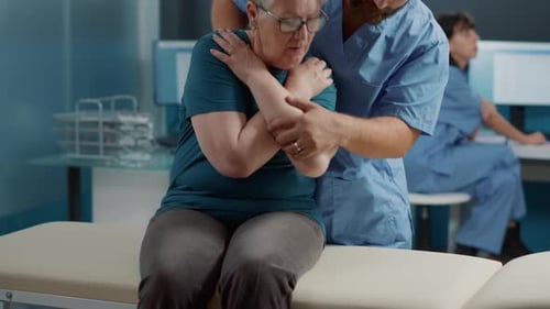 Doctor Adjusting Senior Woman's Arm in Clinic