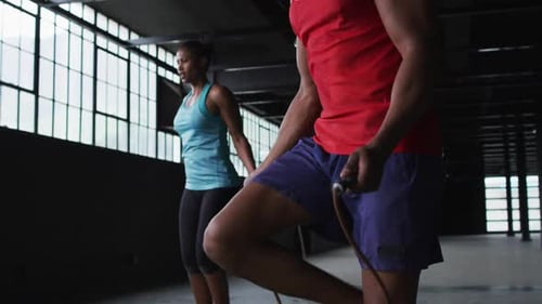 African american man and woman skipping rope in an empty urban building