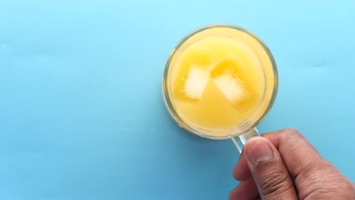 Top View of a Glass of Orange Juice with Iece on Blue Background