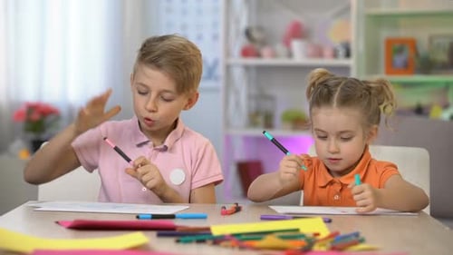 Children Draw Pictures Together at Table Indoors