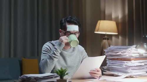 Man Drinks Coffee while Working Late at Desk