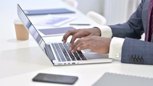 Close Up of African Man Typing on Laptop in Office