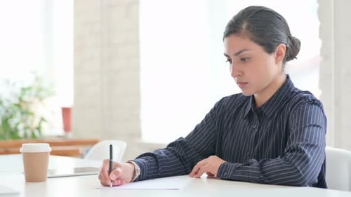 Woman Writing at Desk in Bright Office