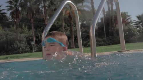 Child having fun in swimming pool and splashing water