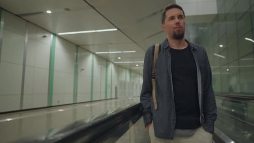 Man Travels on Moving Walkway in Urban Terminal