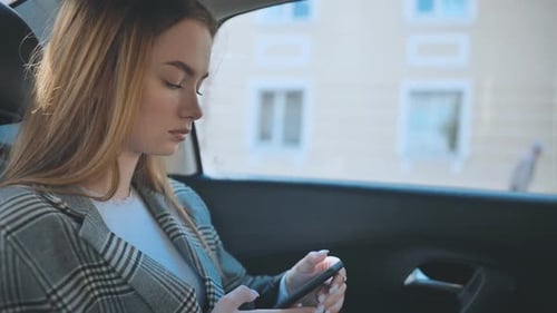 Young Woman Using Mobile Phone in Car