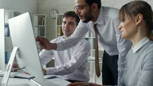 Three People Collaborating on a Computer in Office