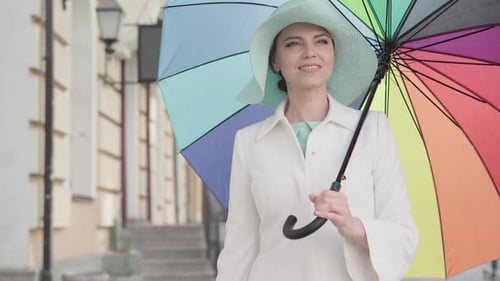 Camera Approaches To Elegant Adult Caucasian Woman Standing Outdoors with Colorful Umbrella and