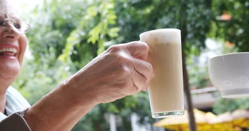 Senior women toasting coffee cup and a mug in the cafe