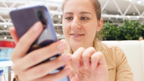 Woman Smiling and Using Smartphone Indoors Close Up