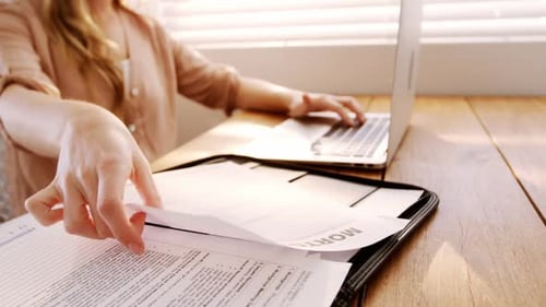 Woman looking at bill while using laptop