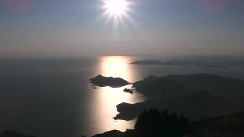Gleitschirmflieger fliegen mit Gleitschirmfliegen im Himmel über Wald, Berggipfel und Meer