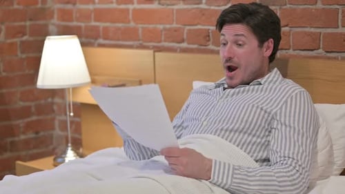 Man in Bed Reading and Taking Notes