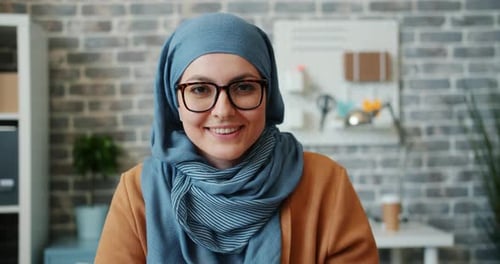 Zeitlupe eines hübschen Mädchens im Hijab lächelnd in die Kamera im Büro