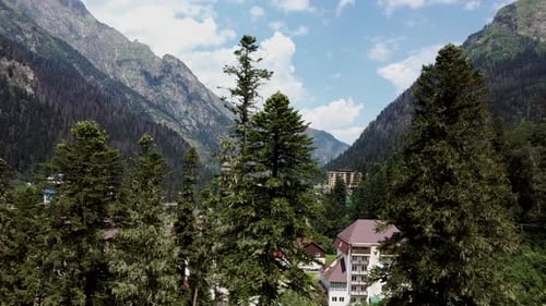 Aerial View of Village in Mountainous and Wooded Areas. Bird's Eye View of Countryside in Summertime