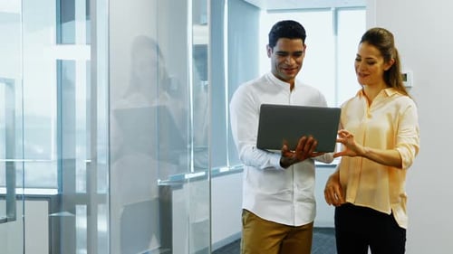 Coworkers Reviewing Laptop Together in Modern Office