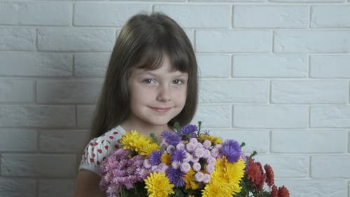 Smiling Girl Holds Colorful Flower Bouquet Indoors