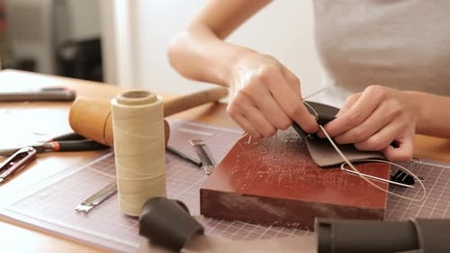Woman Hand Stitches Leather at Table