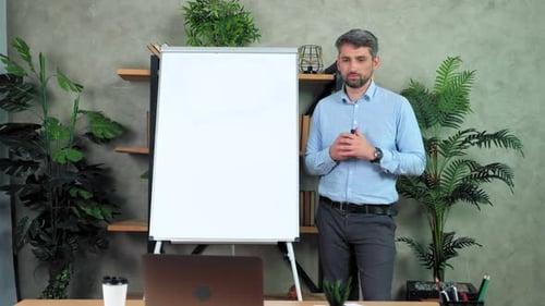 Businessman coach near whiteboard greets listen talk teaches online video call