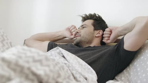 Man Wakes Up and Stretches in Bed