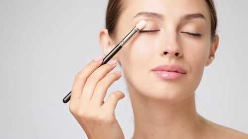 Woman Applies Eye Shadow with Makeup Brush