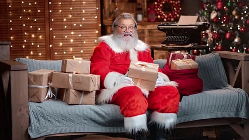 Adorable Male Santa Claus with Christmas Gift Box Posing at Garland Home