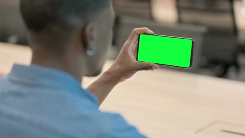 Young Adult Holding Phone with Green Screen in Office