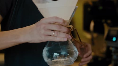 Barista making Filter coffee by spilling hot water through a layer of ground coffee on the filter