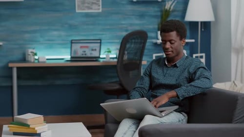 Young Man Typing on Laptop at Home