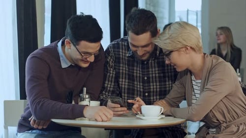 Friends Using Smartphone in Bright Cafe