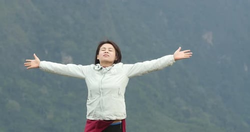 Woman Extends Arms Outward on Mountain Range
