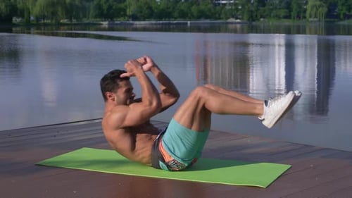 Sportler ohne Hemd auf grüner Yogamatte liegend und trainiert