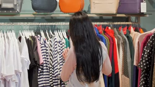 Woman Browsing Clothing in Fashion Store