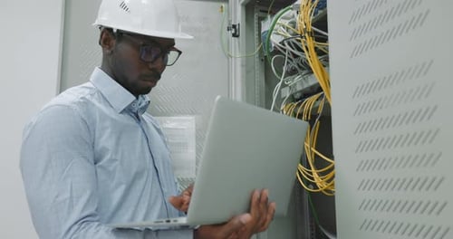 Engineer Uses Laptop to Inspect Server Equipment
