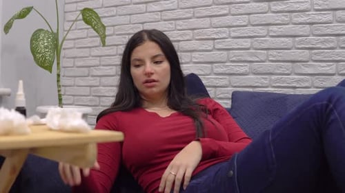 Sick Woman Lying on Sofa with Remote