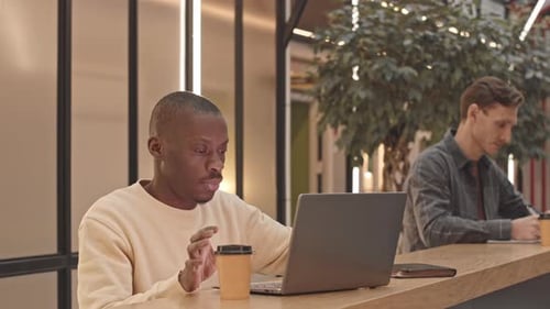 Homme noir travaillant sur ordinateur portable au café