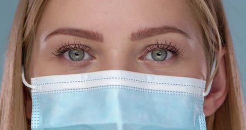 Woman's Eyes Behind Blue Surgical Mask Close-Up