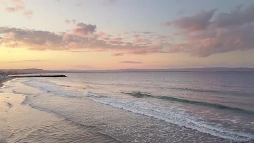 Aerial view of a sea surface with blue water waves under sunset sky.