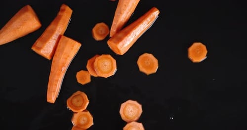 Vibrant Carrots with Water Splash on Black Surface