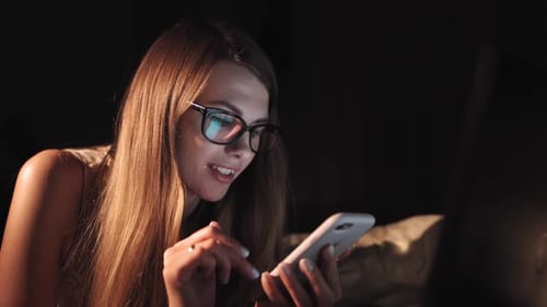 Woman Using Smart Phone in Bed at Night