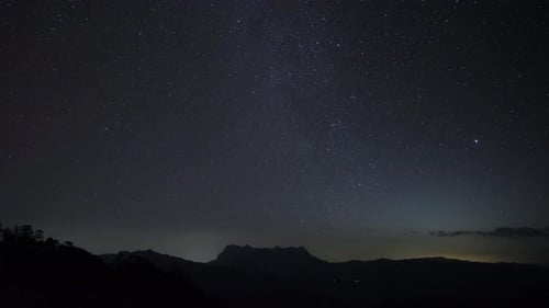 Starry night over mountain time lapse of stars in dark night sky.