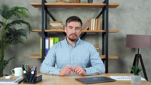 Man Wearing Earbuds Sitting at Desk Working
