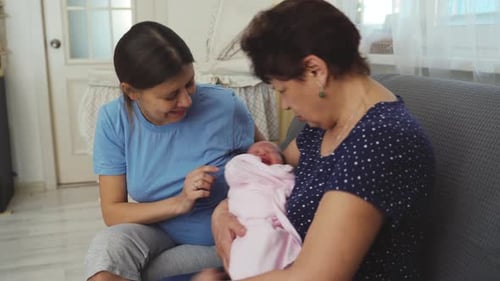 Newborn Infant with Adult Women Sitting on Couch