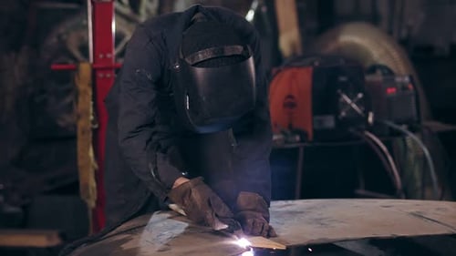 Unrecognizable Workman All Equiped with Protective Wear Cuts Piece of Mettal with an Industrial