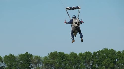 Fallschirmspringer im Tandem fliegen in den Himmel und landen in Zeitlupe auf dem Feld