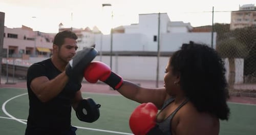 Woman Boxing with Trainer in Urban Setting