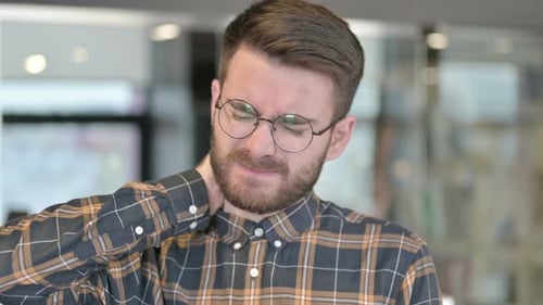 Portrait d'un jeune designer ayant des douleurs au cou au bureau