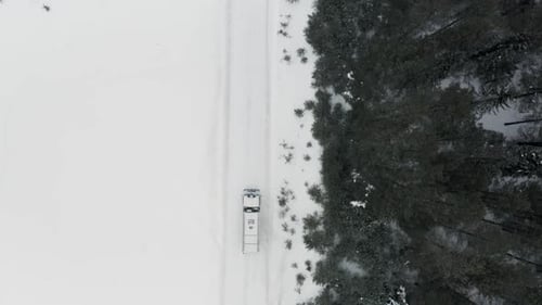 Truck driving on a road surrounded by winter forest