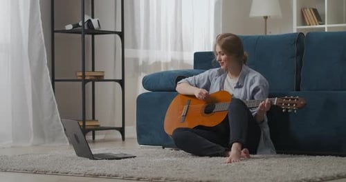 Young Woman Playing Guitar in Living Room